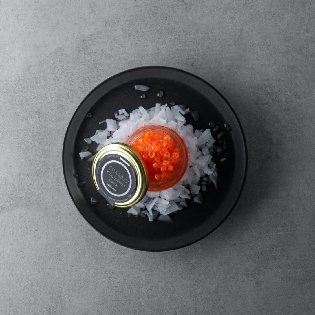 Jar of bright orange salmon caviar on ice